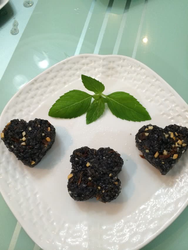 大米团的做法大全图解_图解大全 3. 熟乌米饭里撒一点精盐(爱吃甜的就放糖),倒入牛肉粒、花生碎、一点点橄榄油,拌匀。手上也倒一点橄榄油,取一团拌好的饭团压入模具,尽量压实,脱模即可