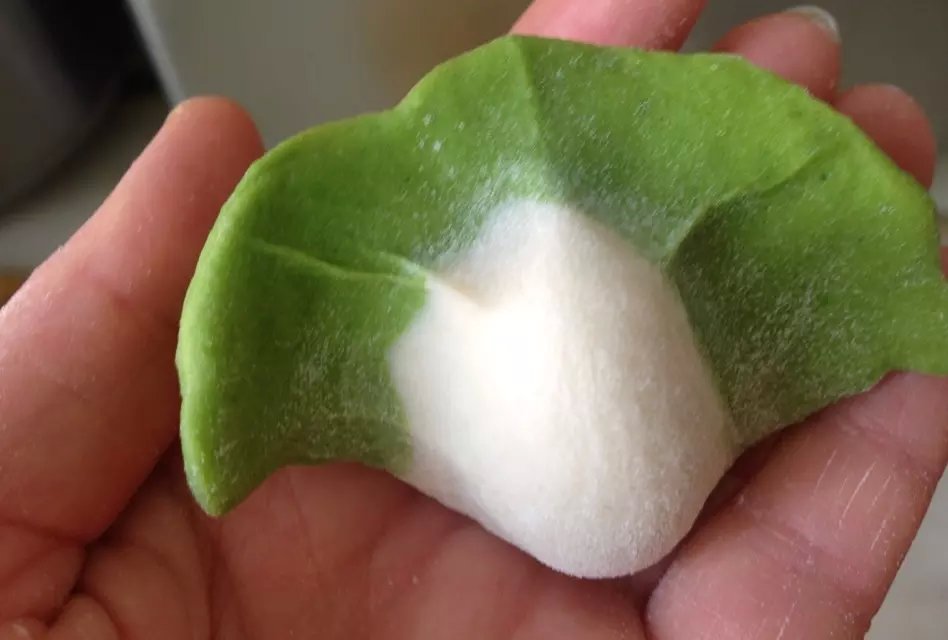 然后将饺子皮放在两手食指上,用两个大拇指往食指上推一下,两个虎口
